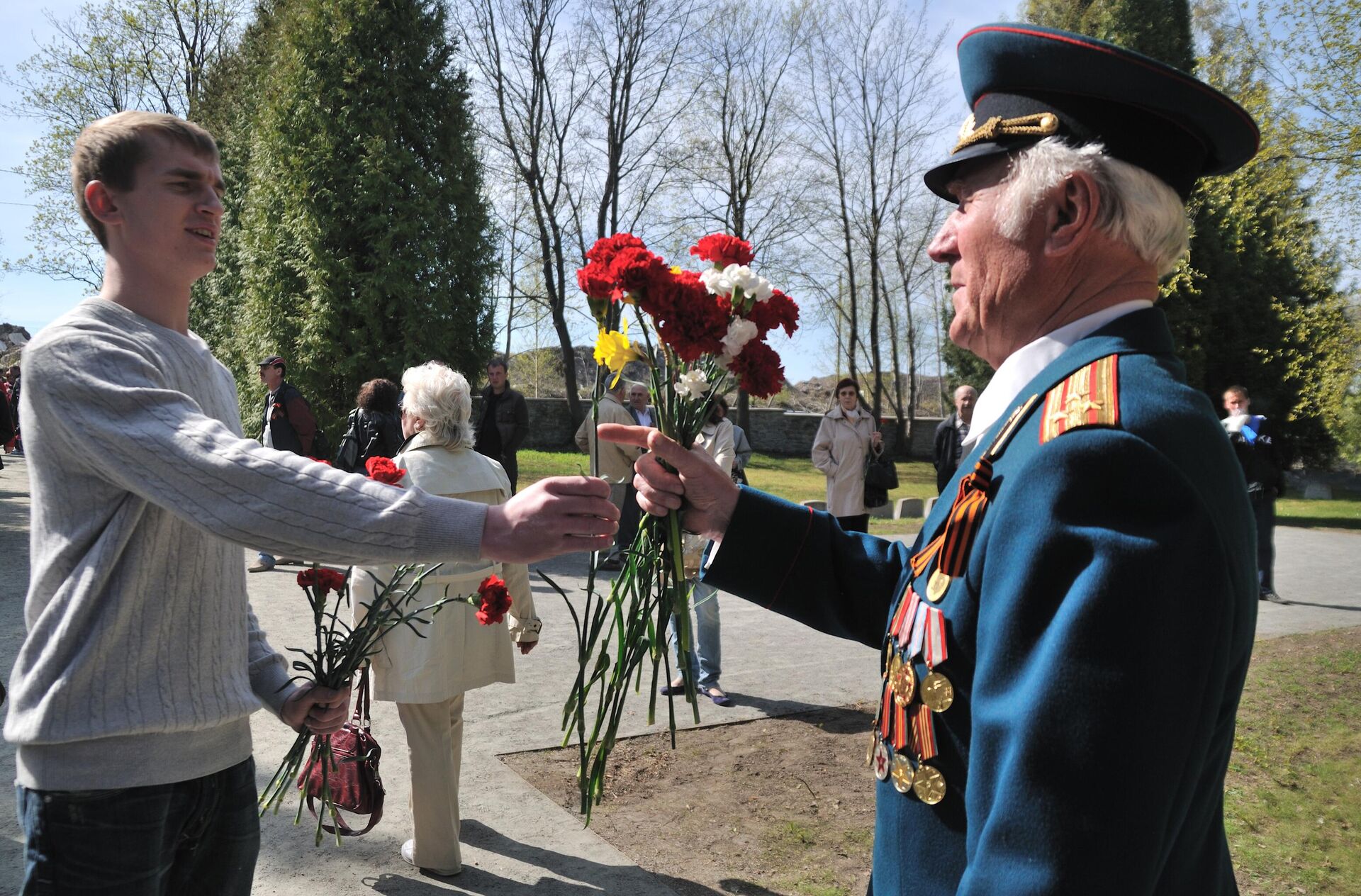 A young man gives a Great Patriotic War veteran flowers on May 9th at the Liberator Soldier monument (also known as the Bronze Soldier) located in a military cemetery in Tallinn, Estonia. - Sputnik International, 1920, 22.09.2024