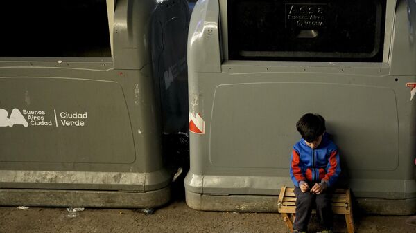 Boy sits on the sidewalk next to public trash containers in Buenos Aires, Argentina, Tuesday, Sept. 3, 2024. - Sputnik International