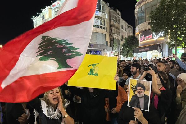 Palestinian protesters carry Lebanese flags, Hezbollah flags and posters with a picture of late Nasrallah during a rally in support of the movement, in the West Bank city of Ramallah. - Sputnik International