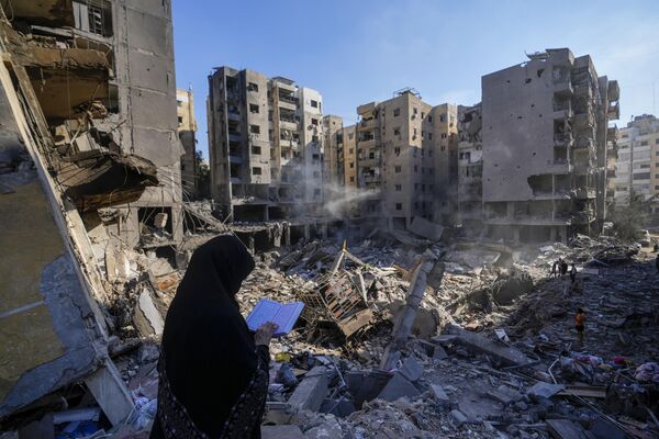 A woman reads the Quran at the site of the Nasrallah&#x27;s assassination in Beirut&#x27;s southern suburbs. - Sputnik International