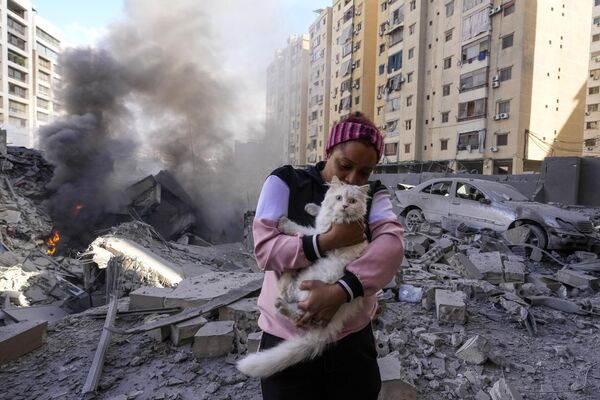 A woman holds her cat in front of a destroyed building at the site of an Israeli airstrike in Dahieh, Beirut, Lebanon, October 2, 2024. - Sputnik International