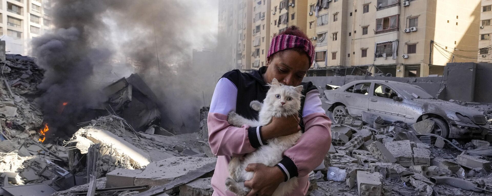 A woman holds her cat in front of a destroyed building at the site of an Israeli airstrike in Dahiyeh, Beirut, Lebanon - Sputnik International, 1920, 03.10.2024