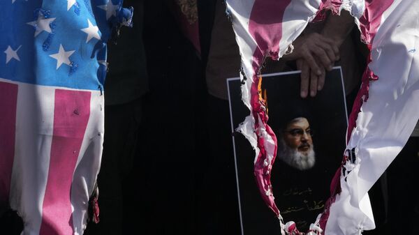 A representation of the US flag is set on fire as a demonstrator holds a poster of slain Hezbollah leader Hassan Nasrallah in a rally commemorating him, in Tehran, Iran, Wednesday, Oct. 2, 2024 - Sputnik International