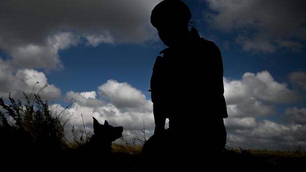 A Russian serviceman of an anti-aircraft missile unit of the Russian Tsentr Battlegroup is seen with a service dog at a position in the Avdeyevka sector of the frontline amid Russia's military operation in Ukraine, Russia. - Sputnik International