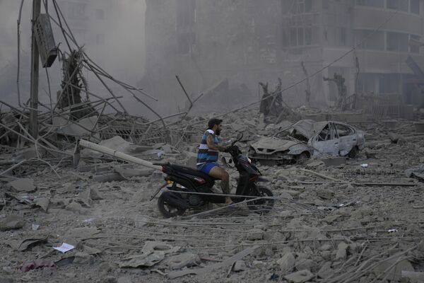 A man rides his scooter as he drives over the debris of destroyed buildings hit by Israeli airstrikes in Dahiyeh, Beirut. - Sputnik International