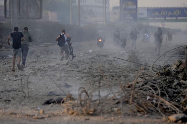 People run over the rubble of destroyed buildings hit by Israeli airstrikes in Dahiyeh, Beirut. - Sputnik International