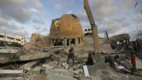 People stand outside a mosque destroyed in an Israeli air strike in Khan Younis, Gaza Strip, Sunday, Oct.8, 2023.  - Sputnik International