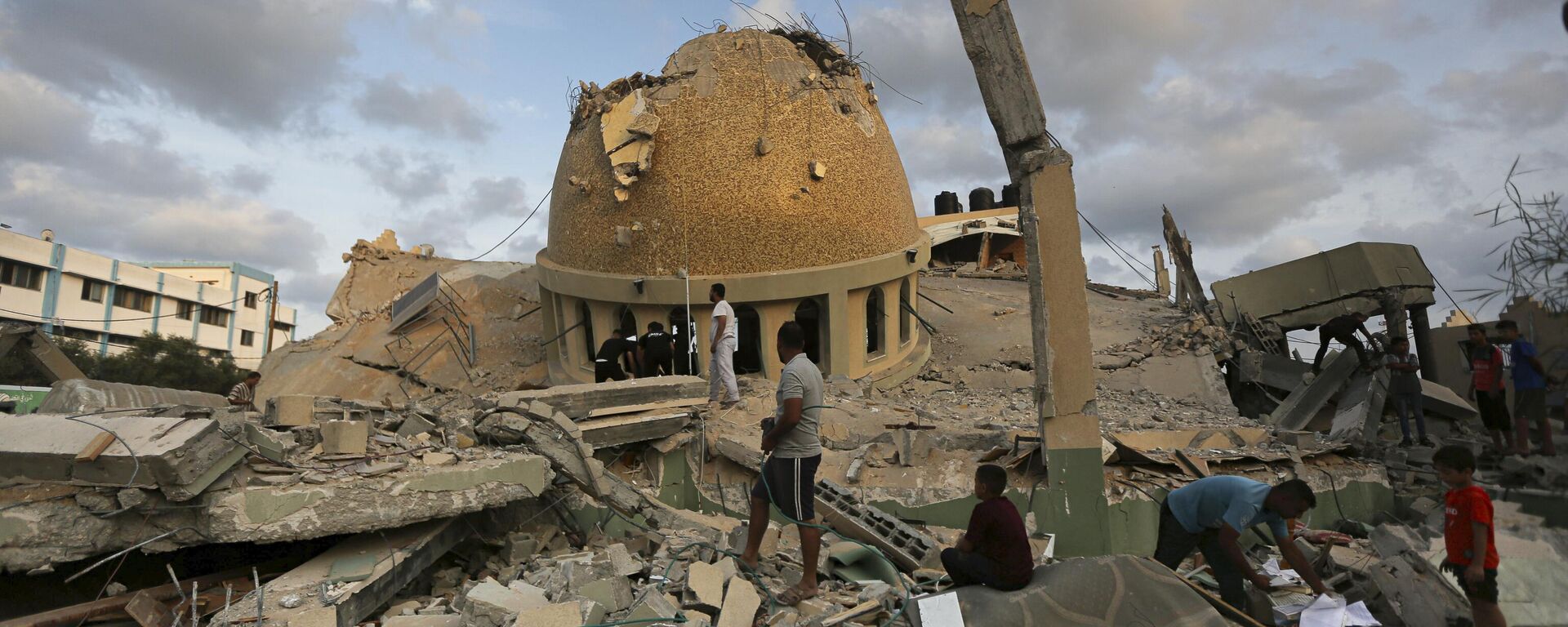 People stand outside a mosque destroyed in an Israeli air strike in Khan Younis, Gaza Strip, Sunday, Oct.8, 2023.  - Sputnik International, 1920, 06.10.2024