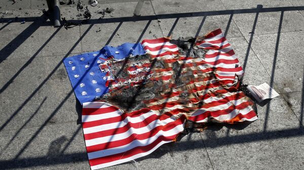 A burnt copy of a United Stated flag lays in front of the Palace of La Moneda, after it was lit by a single man to protest against the visit of US Vice President Mike Pence, in Santiago, Chile, Wednesday, Aug. 16, 2017 - Sputnik International