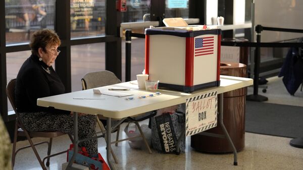 A poll worker is seated near a ballot box during early voting in the general election, Friday, Nov. 1, 2024, in Fall River, Mass.  - Sputnik International