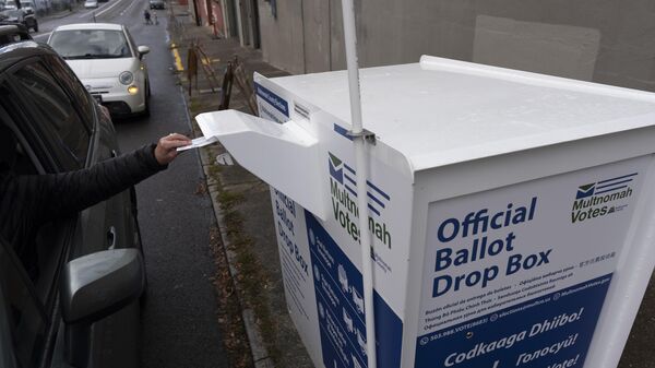 A person drops off their 2024 election ballot at a newly installed drop box outside the Multnomah County Elections Division office on Monday, Oct. 28, 2024, in Portland, Ore.  - Sputnik International