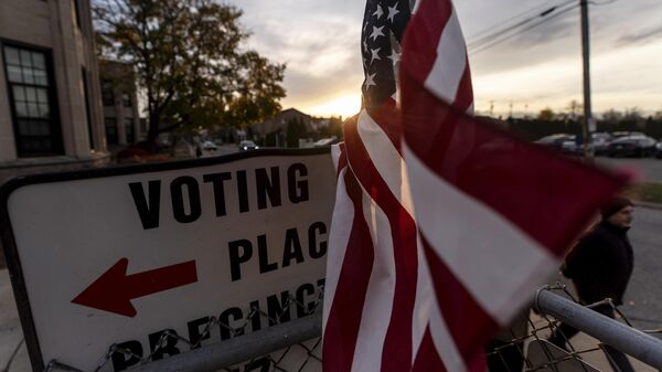 An American flag flies in the wind as a voter leaves a polling site after casting a ballot on Election Day - Sputnik International