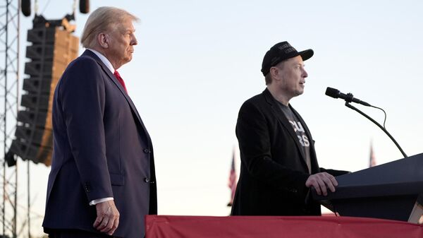 Tesla and SpaceX CEO Elon Musk speaks as Donald Trump listens at a campaign event at the Butler Farm Show, Saturday, Oct. 5, 2024. - Sputnik International