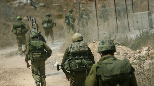 Israeli reservists walk along a dirt road on the Lebanon side of the border after crossing from northern Israel.  - Sputnik International