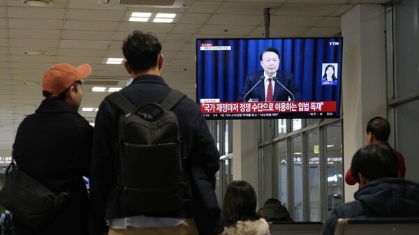 People watch a TV screen showing South Korean President Yoon Suk Yeol's televised briefing at a bus terminal in Seoul, South Korea, Tuesday, Dec. 3, 2024.  - Sputnik International