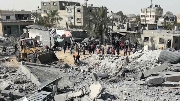 Palestinians gather near a building destroyed by Israeli airstrikes in the city of Khan Younis, southern Gaza Strip, Friday, Oct. 25, 2024.  - Sputnik International