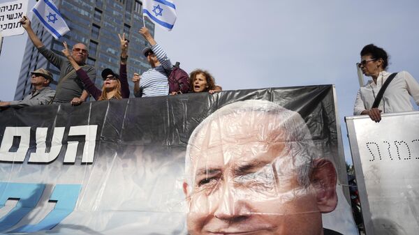 Supporters of Israel's Prime Minster Benjamin Netanyahu, seen in poster, gather outside a  court in Tel Aviv, Israel, Tuesday, Dec. 10, 2024 as Netanyahu is set to take the stand in his long-running trial on corruption charges. - Sputnik International