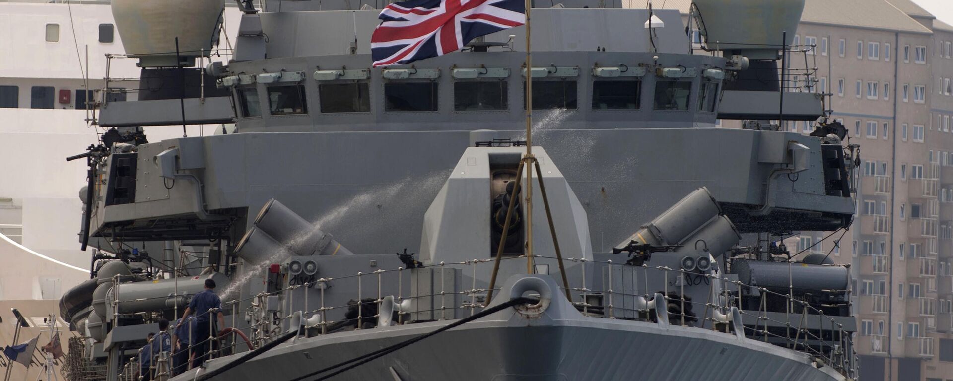 A crew member uses a water hose onboard Britain's Royal Navy warship HMS Westminster in Gibraltar, Monday, Aug. 19, 2013 after the ship arrived for what Britain's government said was a planned naval exercise in the Mediterranean - Sputnik International, 1920, 23.05.2025