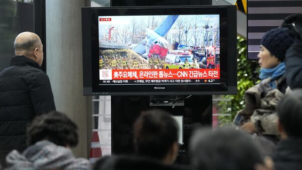 Relatives of passengers watch the news regarding the plane crash at Muan International Airport in Muan, South Korea, Sunday, Dec. 29, 2024.  - Sputnik International