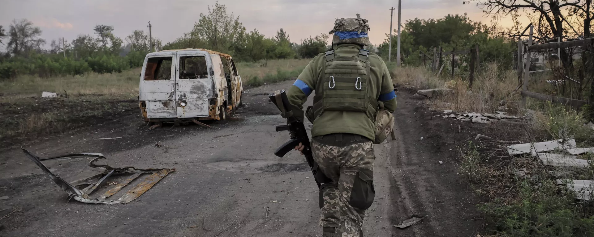 A serviceman of the 24th Mechanised Brigade runs past a damaged car at the frontline in Donetsk region.   - Sputnik International, 1920, 03.01.2025