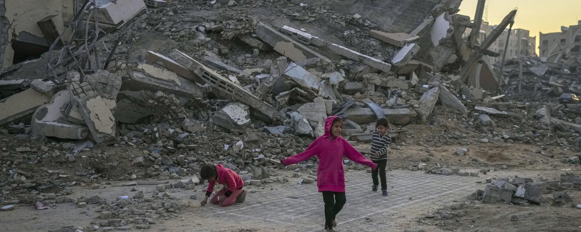 Palestinian children next to a building destroyed by Israeli army strikes in the central Gaza Strip town of Khan Younis, Wednesday, Jan. 1, 2025. - Sputnik International, 1920, 02.09.2025