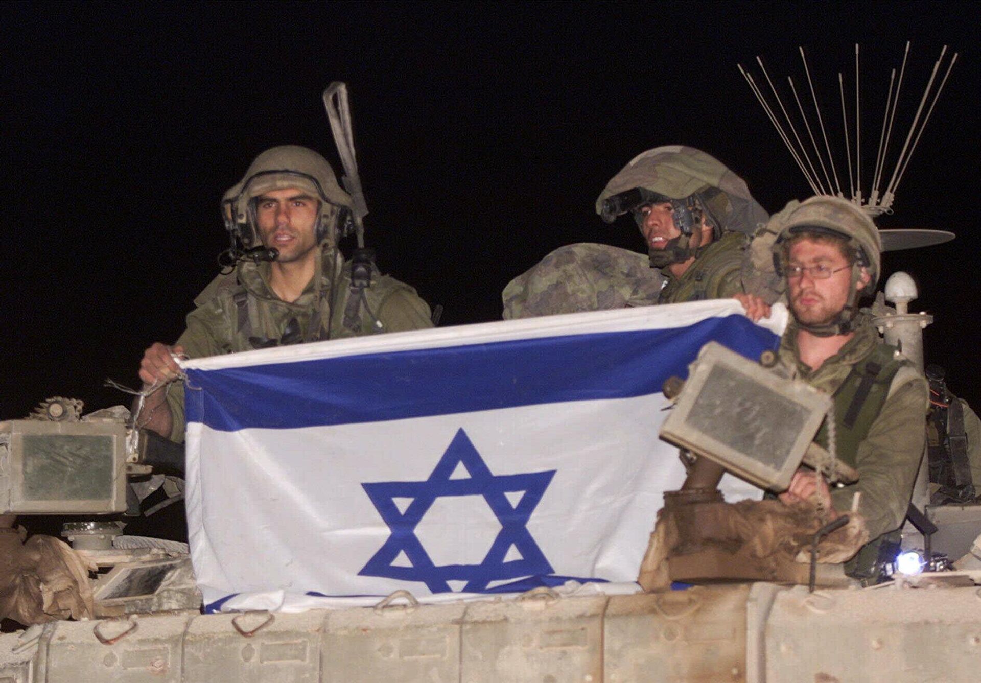 Israeli soldiers ride atop their armored vehicle holding an Israeli flag as they withdraw from south Lebanon into Israel, at the Israeli-Lebanese border near Metulla, early Wednesday, May 24, 2000.  - Sputnik International, 1920, 04.01.2025