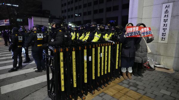 Supporters of impeached South Korean President Yoon Suk Yeol, hold signs with a message that translates to; Release the president, alongside police officers, outside the Western District Court in Seoul, South Korea, Sunday, Jan. 19, 2025.  - Sputnik International