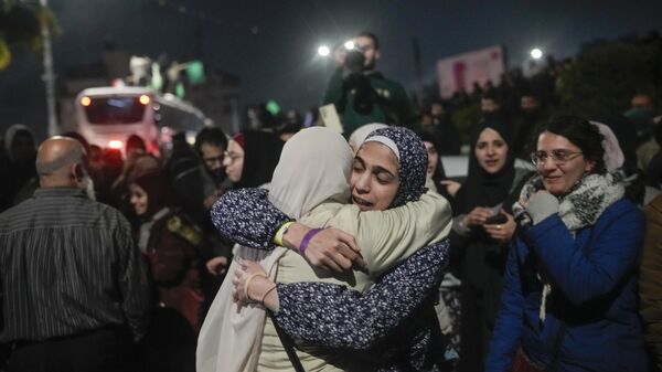 A female Palestinian prisoner, center left, is greeted after disembarking from a bus following her release from an Israeli prison, in the West Bank city of Beitunia. - Sputnik International