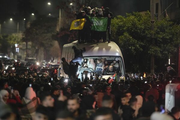 A crowd gathers around a bus carrying released Palestinian prisoners as it arrives in the West Bank city of Beitunia. - Sputnik International