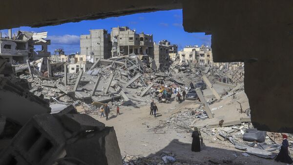 Palestinians walk through the rubble caused by the Israeli air and ground offensive in Rafah, southern Gaza Strip, Monday, Jan. 20, 2025. - Sputnik International