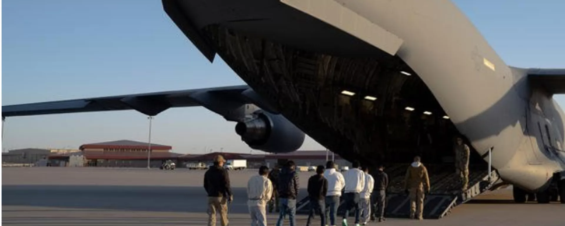 Screenshot of image showing U.S. Customs and Border Protection security agents guide a group of migrants to board a C-17 Globemaster III aircraft assigned to the 60th Air Mobility Wing for a removal flight at Fort Bliss, Texas, on Jan. 23, 2025.  - Sputnik International, 1920, 27.01.2025