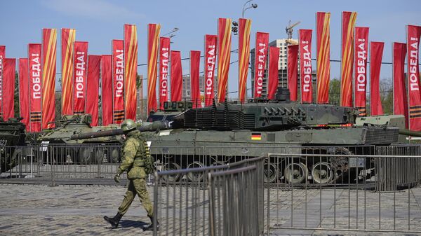 A Russian soldier walks past a Leopard 2A6 tank that belonged to the Ukrainian army is seen on display in Moscow. Tuesday, April 30, 2024. - Sputnik International