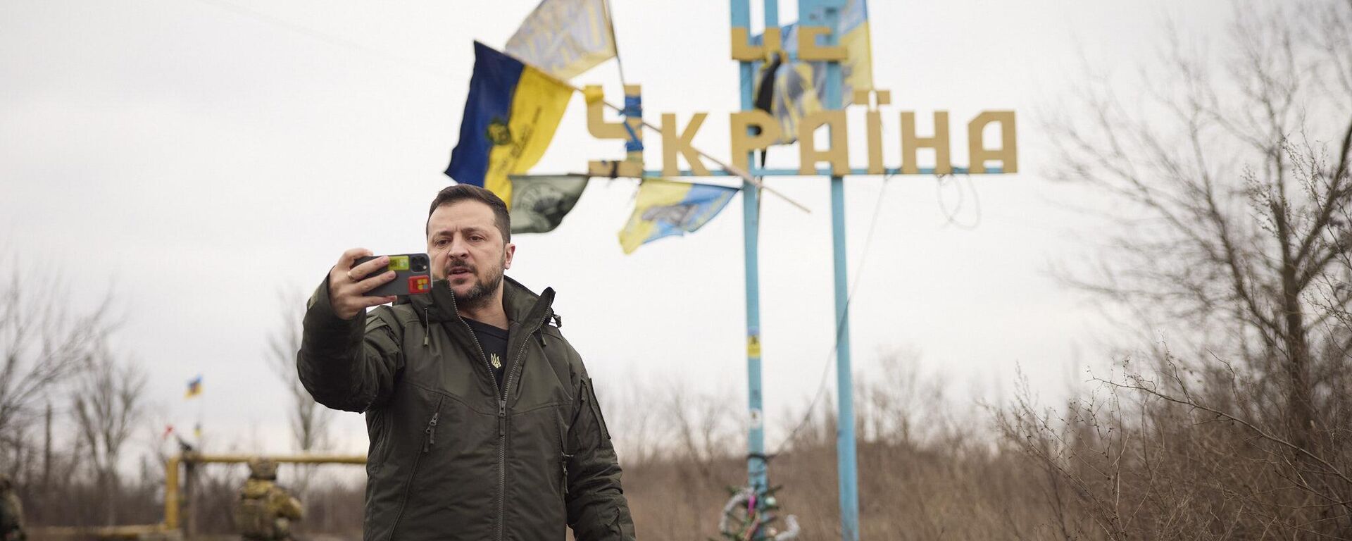 In this photo provided by the Ukrainian Presidential Press Office, Ukrainian President Volodymyr Zelenskyy visits Avdeyevka, the site of fierce battles with the Russian troops in the Donetsk region, Ukraine, Friday, Dec. 29, 2023. Sign reading Avdiivka is seen in the background.  - Sputnik International, 1920, 19.02.2025