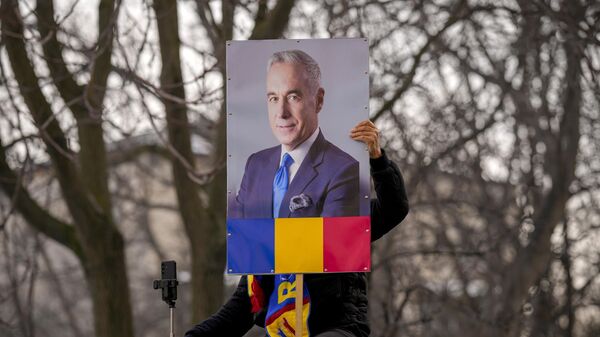 A man holds a portrait of Calin Georgescu, the winner of Romania's first round of presidential election, annulled by the Constitutional Court. File photo - Sputnik International