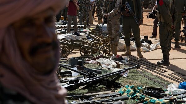 Malian soldiers look on as weapons, munitions, and other paraphernalia seized from radical Islamist militants are displayed at the French army base in Gao, Mali, Sunday, Feb. 24, 2013 - Sputnik International