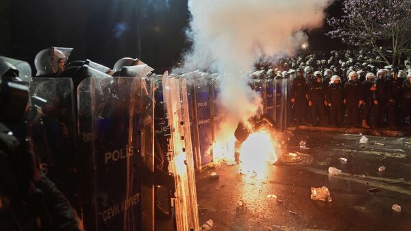 A protester holds a flare next to riot police officers during a protest against the arrest of Istanbul Mayor Ekrem Imamoglu, in Istanbul, Turkey, Saturday, March 22, 2025 - Sputnik International