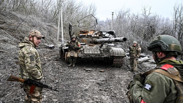 Russian servicemen seen next to a destroyed Ukrainian T-64 tank amid Russia's military operation in Ukraine, in the village of Russkoye Porechnoye, Kursk region, Russia. - Sputnik International