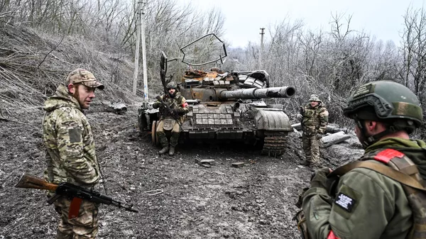 Russian servicemen seen next to a destroyed Ukrainian T-64 tank amid Russia's military operation in Ukraine, in the village of Russkoye Porechnoye, Kursk region, Russia. - Sputnik International