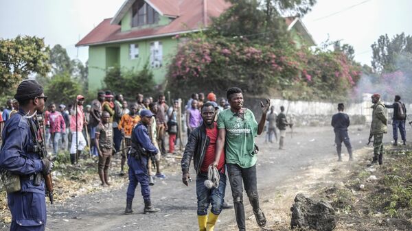 A wounded demonstrator walks past police officers during a protest against the United Nations peacekeeping force deployed in the Democratic Republic of the Congo in Sake, some 15 miles (24 kms) west of Goma, Wednesday July 27, 2022.  - Sputnik International