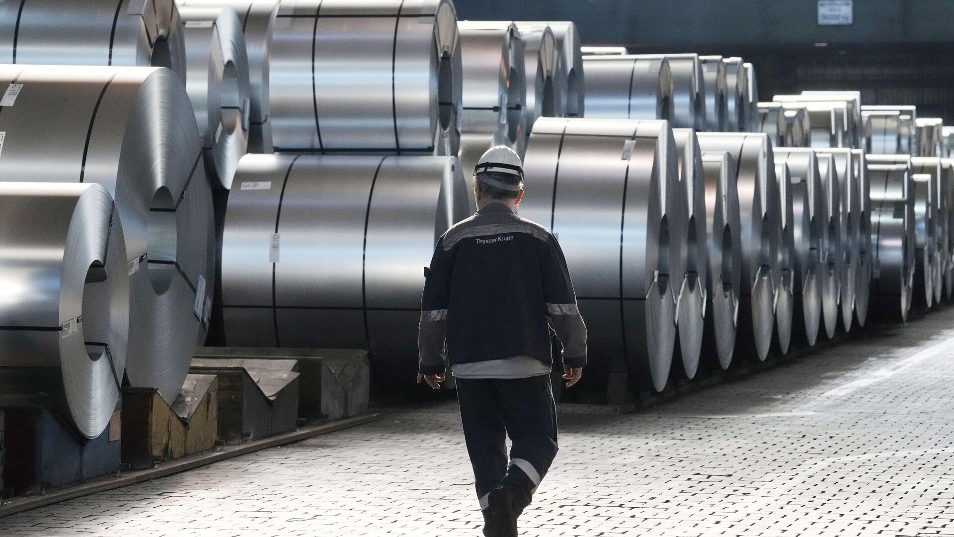 A steel worker walks beside steel coils during a visit of EU Commissioner for Prosperity and Industrial Strategy Stephane Sejourne at the Thyssenkrupp steelworks in Duisburg, Germany, on March 20, 2025.  - Sputnik International, 1920, 12.11.2025