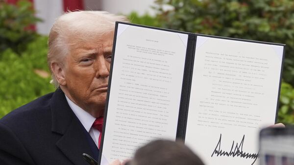 President Donald Trump holds a signed executive order during an event to announce new tariffs in the Rose Garden of the White House, Wednesday, April 2, 2025, in Washington - Sputnik International
