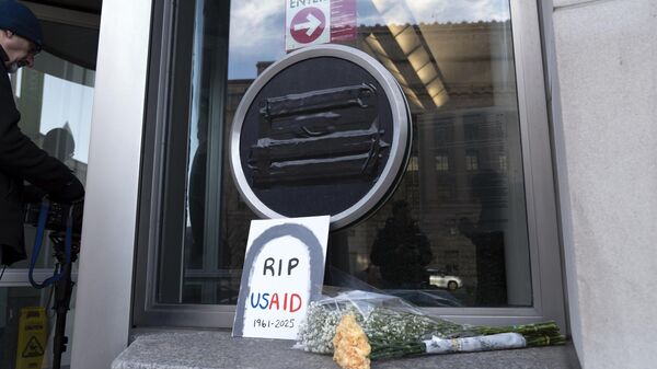 Flowers and a sign are placed outside the headquarters of the U.S. Agency for International Development, or USAID, Friday, Feb. 7, 2025, in Washington.  - Sputnik International
