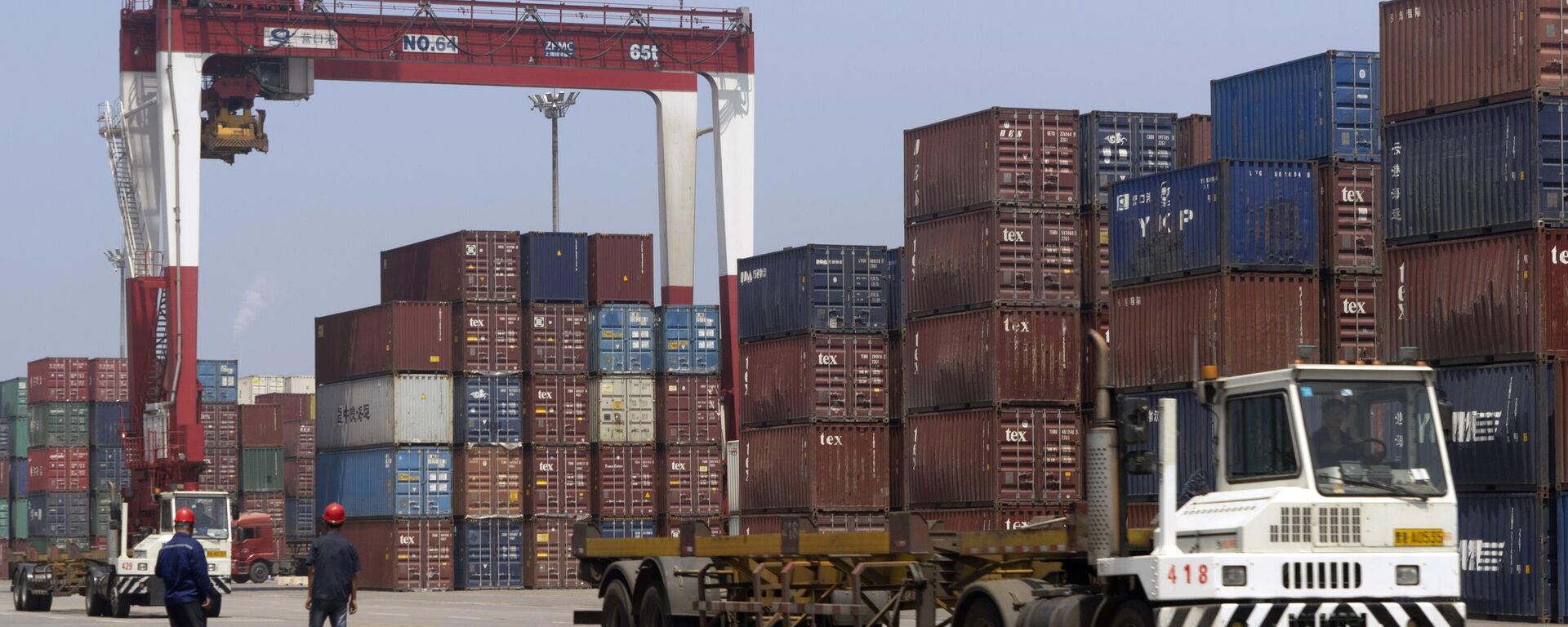 Workers watch as a truck passes by stacks of shipping containers at a port in Yingkou in northeastern China's Liaoning Province.  - Sputnik International, 1920, 24.04.2026