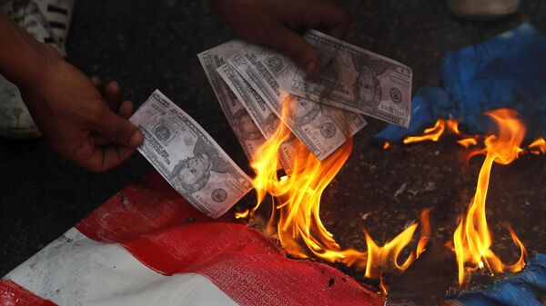 A supporter of a communist group burns representation of U.S. currency, during a protest against U.S. interference in Lebanon's affairs, near the U.S. embassy, in Aukar northeast of Beirut, Lebanon, Friday, July 10, 2020 - Sputnik International
