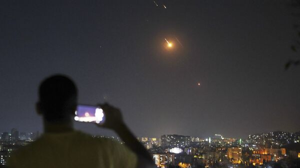 A man takes a cellphone photo as missiles fired from Iran toward Israel fly over Syrian territory in Damascus - Sputnik International