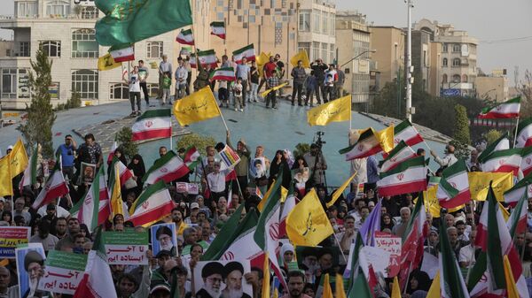 Iranian protesters wave their country's flags and banners containing slogans in support of Supreme Leader Ayatollah Ali Khamenei in an anti-U.S. and anti-Israeli rally at Enqelab-e-Eslami (Islamic Revolution) square in downtown Tehran, Iran, Tuesday, June 24, 2025. - Sputnik International