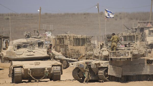 Israeli soldiers work on their tanks in a staging area on the border with Gaza Strip, in southern Israel, Tuesday, July 29, 2025 - Sputnik International