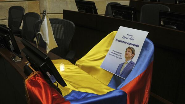 FILE - A leaflet showing Colombian Sen. Miguel Uribe Turbay sits on a Colombian national flag draped over his seat in the congressional chamber in Bogota, Colombia, June 9, 2025. (AP Photo/Ivan Valencia, File) - Sputnik International