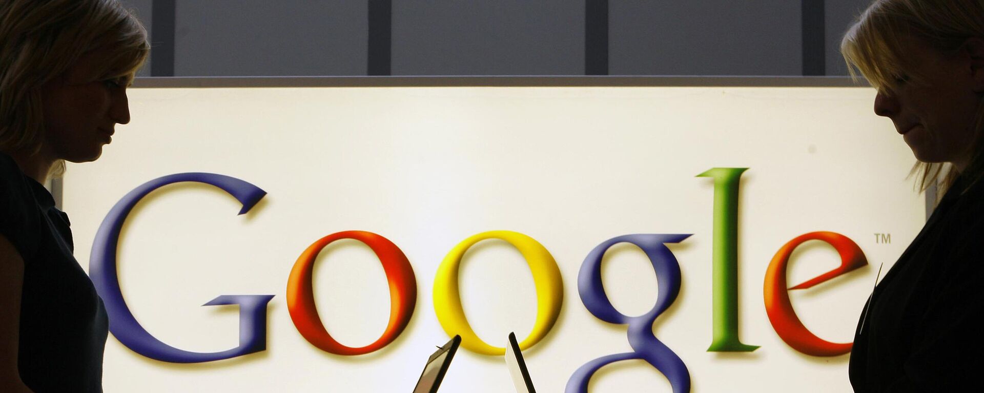 In this April 17, 2007 file photo, exhibitors work on laptop computers in front of an illuminated sign of the Google logo at the industrial fair Hannover Messe in Hanover, Germany. - Sputnik International, 1920, 12.08.2025