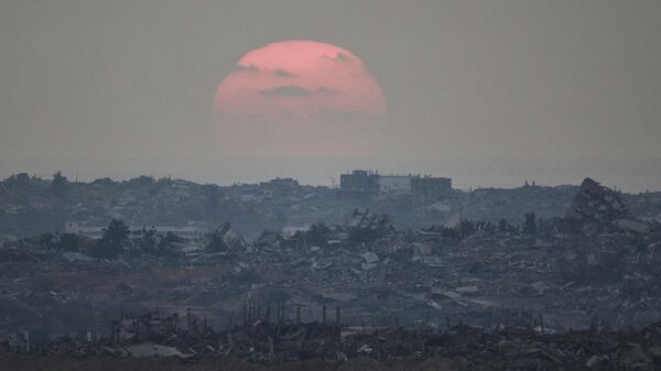 The sun sets behind buildings destroyed during Israeli ground and air operations in the northern Gaza Strip, as seen from southern Israel, Aug. 8, 2025 - Sputnik International